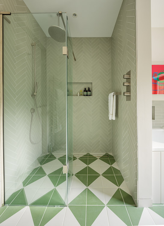 large walk-in shower with green and white tiles 
